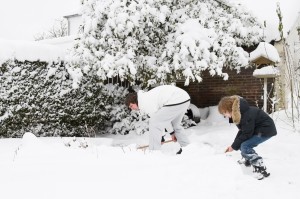 Father And Son Shoveling Snow Together In A Garden