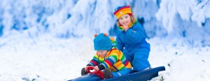 Little girl and boy enjoy a sleigh ride. Child sledding. Toddler kid riding a sledge. Children play outdoors in snow. Kids sled in Alps mountains in winter. Outdoor fun for family Christmas vacation.