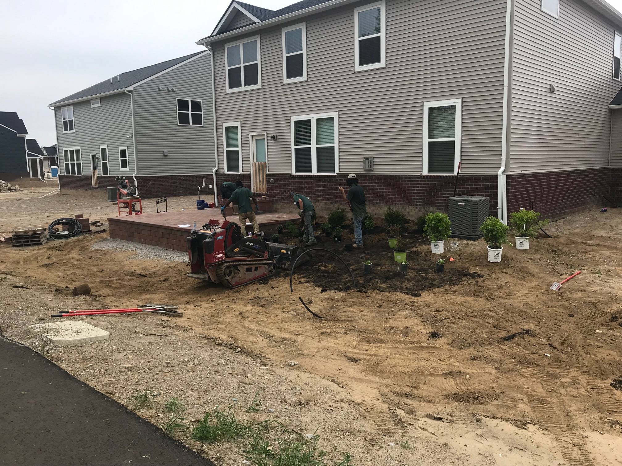 Newly constructed home with new landscape being planted around new backyard patio.