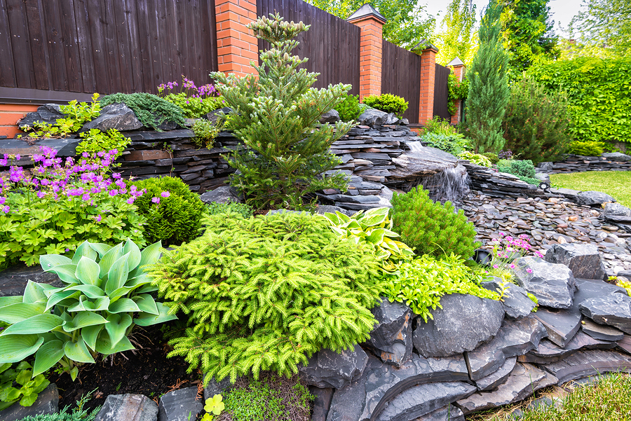 Beautiful residential landscape with flowers, shrubs, and stone.