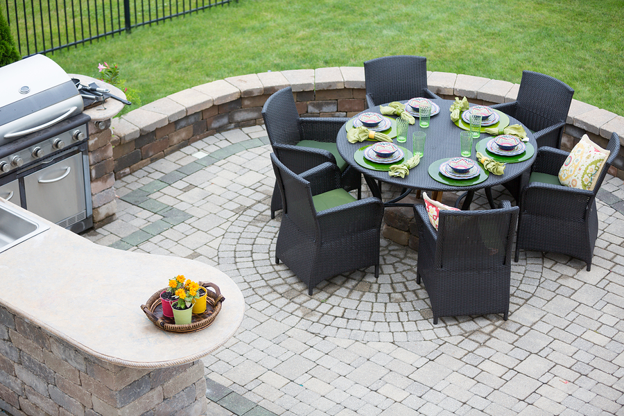 Brick patio with dining table next to an outdoor kitchen area.