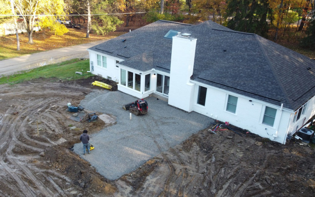 Paver Patio behind a large white house in progress.
