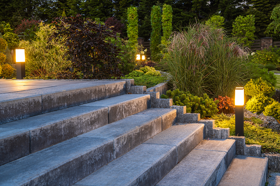 Close up photo of concrete stairs with landscaping plants and post lights along the side