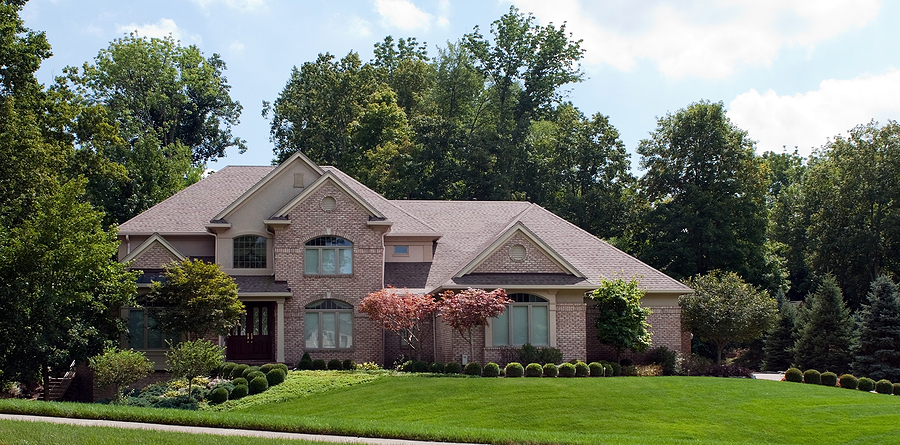 Large brick suburban home with a large landscaped yard. 