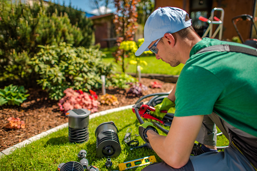 Professional landscaper working on an irrigation system in a backyard. 