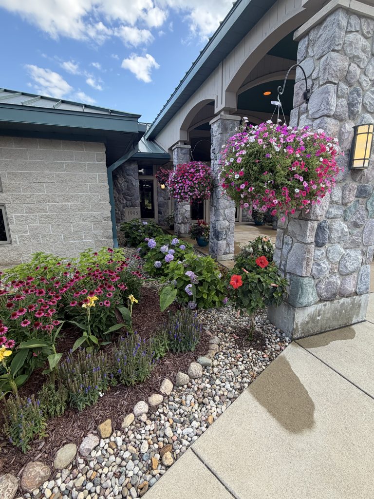 Landscape project with flower beds, trimmed hanging plants, and stone and gravel barrier.