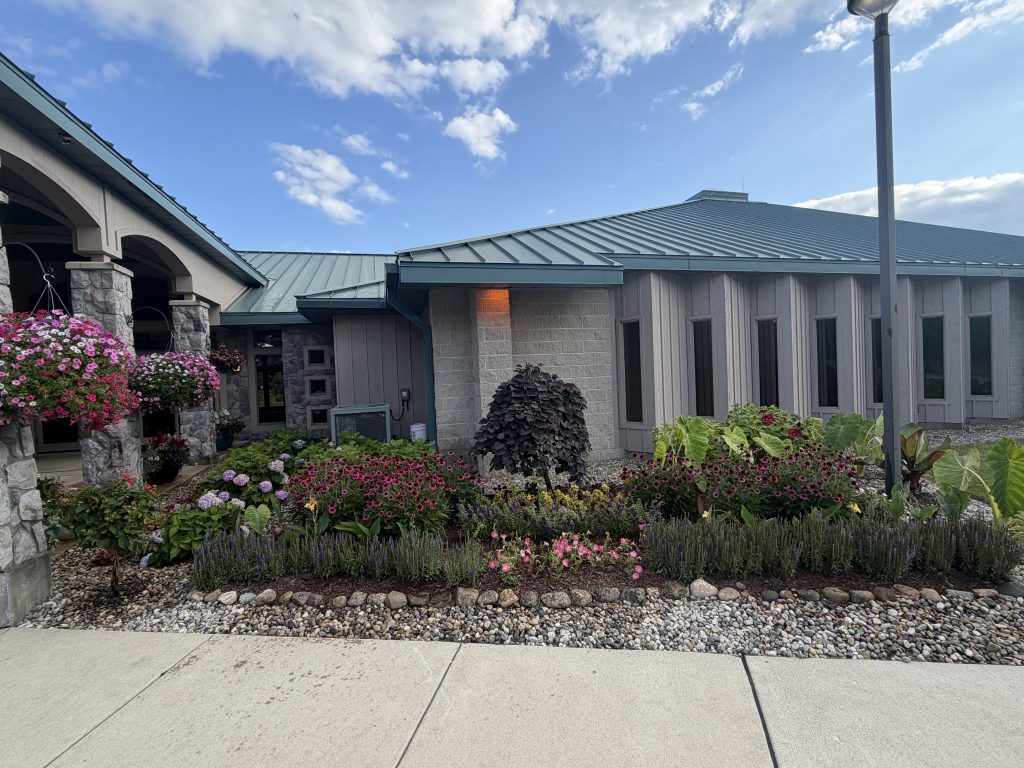 Flowerbeds with stone barrier, details of shrubbery in front of stone commercial building
