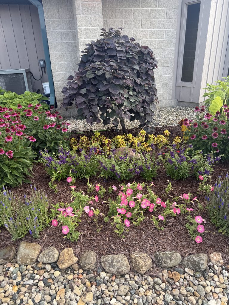 tiered landscaping flower bed with shrubbery and stone paver and gravel boarder