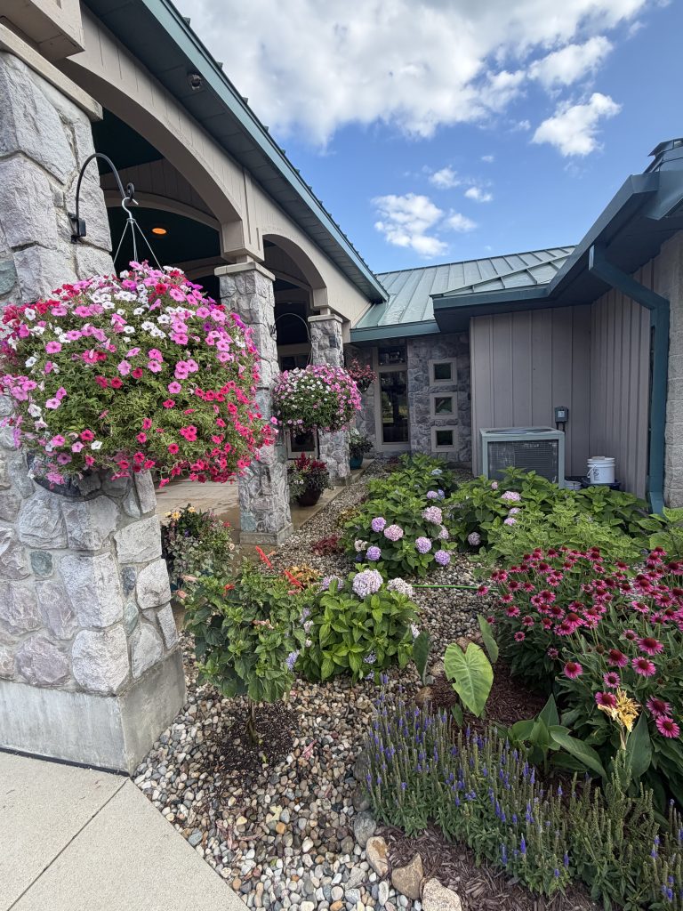 Stone building with landscaping and hanging plants.